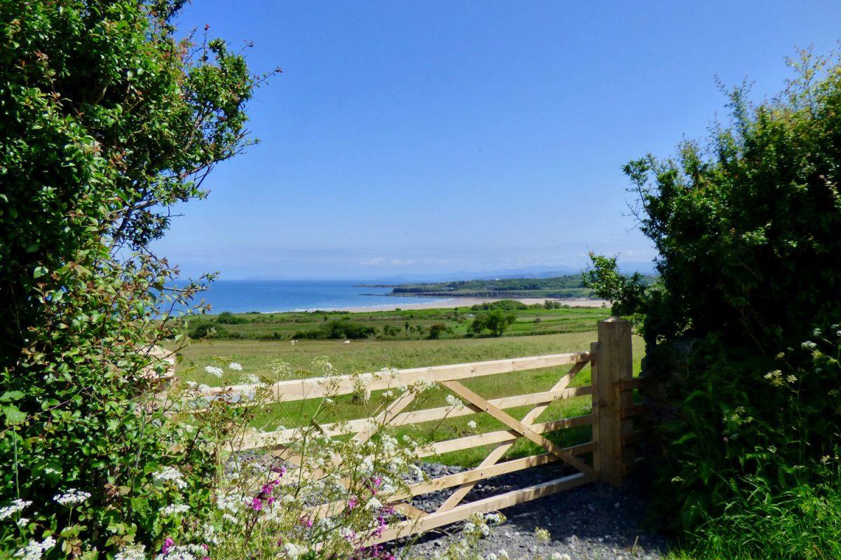 A view of Lligwy Bay from a wooden farm gate.
