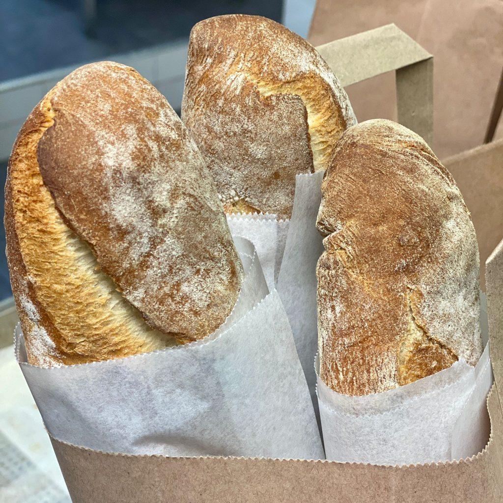 Freshly baked French sticks packed in a reusable paper bag ready for collection.